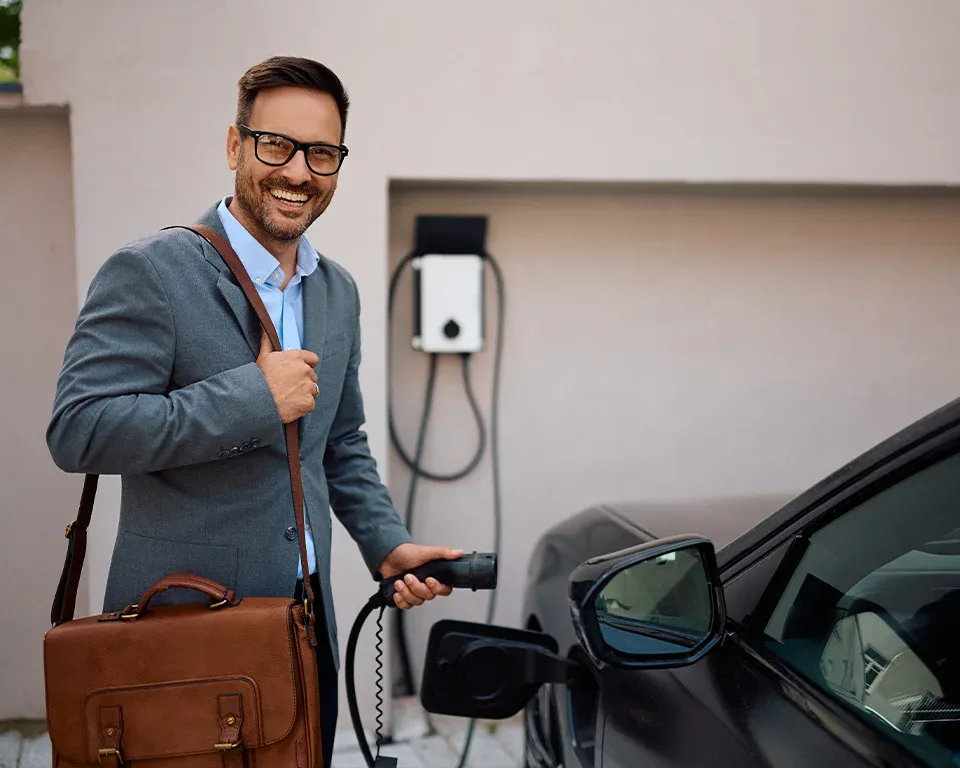 Businessmann einer gro&szlig;en Firma freut sich &uuml;ber sein neues Elektro-Firmenfahrzeug